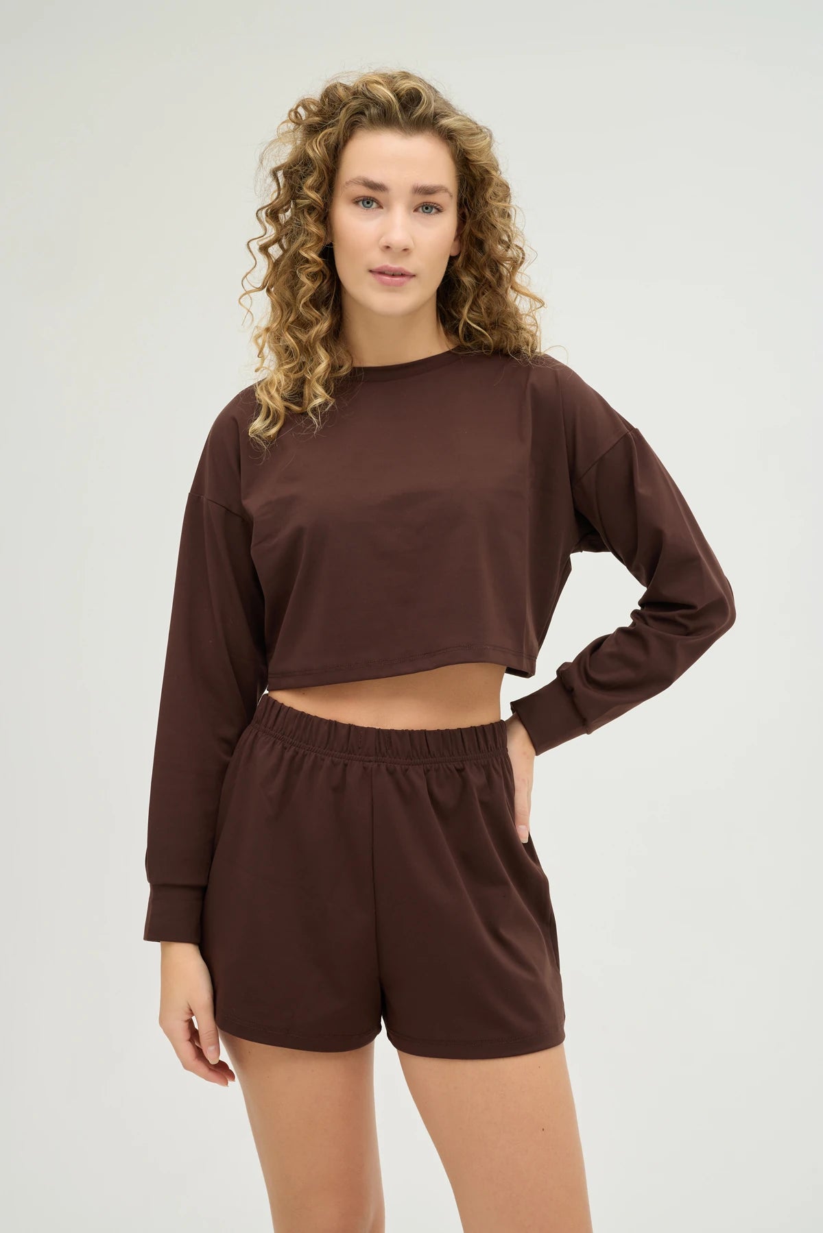 Crop Kahverengi Sweatshirt Takım, şıklık ve konforu bir araya getiren modern bir tasarıma sahiptir. Yumuşak dokulu, nefes alabilir kumaşı sayesinde gün boyu konforlu bir kullanım sunarken, spor aktiviteleri sırasında da hareket özgürlüğü sağlar.