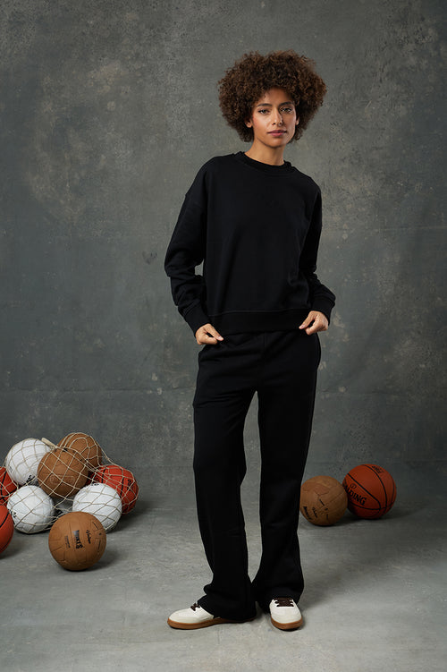 Urban Siyah Kadın Eşofman Altı, konforu ve zarafeti bir arada sunan modern bir tasarımla günlük stilinize eşlik ediyor. Yumuşak dokulu kumaşı ve rahat kesimiyle hareket özgürlüğü sağlarken, yüksek bel yapısı sayesinde vücudu nazikçe sarar ve feminen bir duruş sunar. Minimal detayları ve sade görünümüyle hem spor kombinlere hem de şehir şıklığına kolayca adapte olur. Siyah rengiyle zamansız bir parça olan bu eşofman altı, dolabınızdaki birçok üst giyim parçasıyla uyum sağlar. İster basic tişörtlerle ister sw